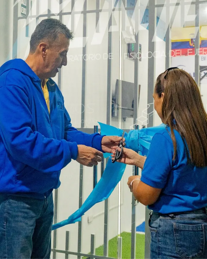 El fundador de LAFIEJ y una colaboradora cortan juntos la cinta turquesa de inauguración, ante la puerta de vidrio del laboratorio